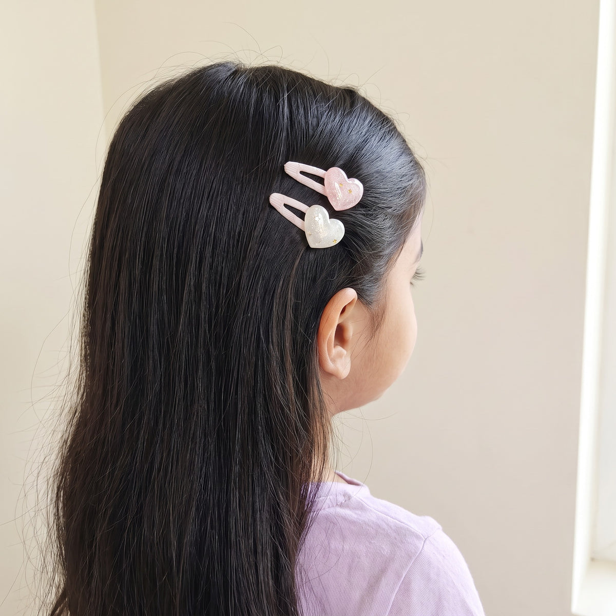 Glitter heart tic tac clips worn in a girl's hair