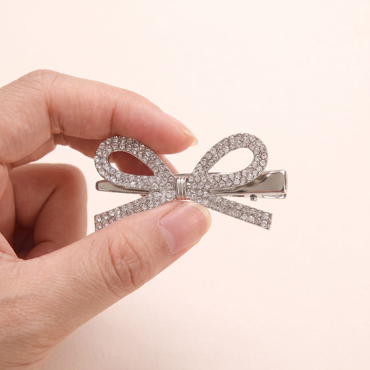 Silver Rhinestone Bow Hairpin held in hand to show size