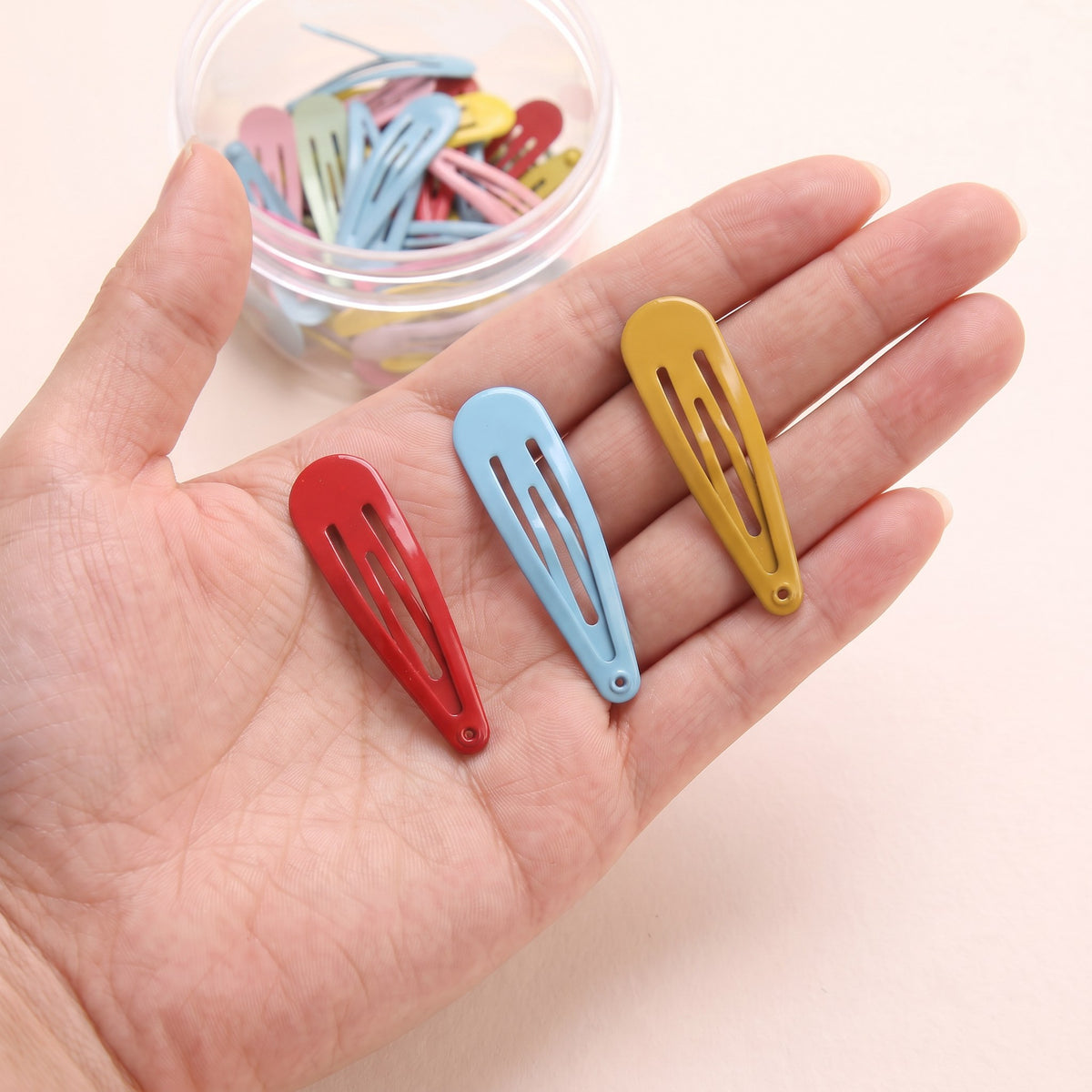 Multicolored tic tac clips held in hand to show the 4.9 cm size