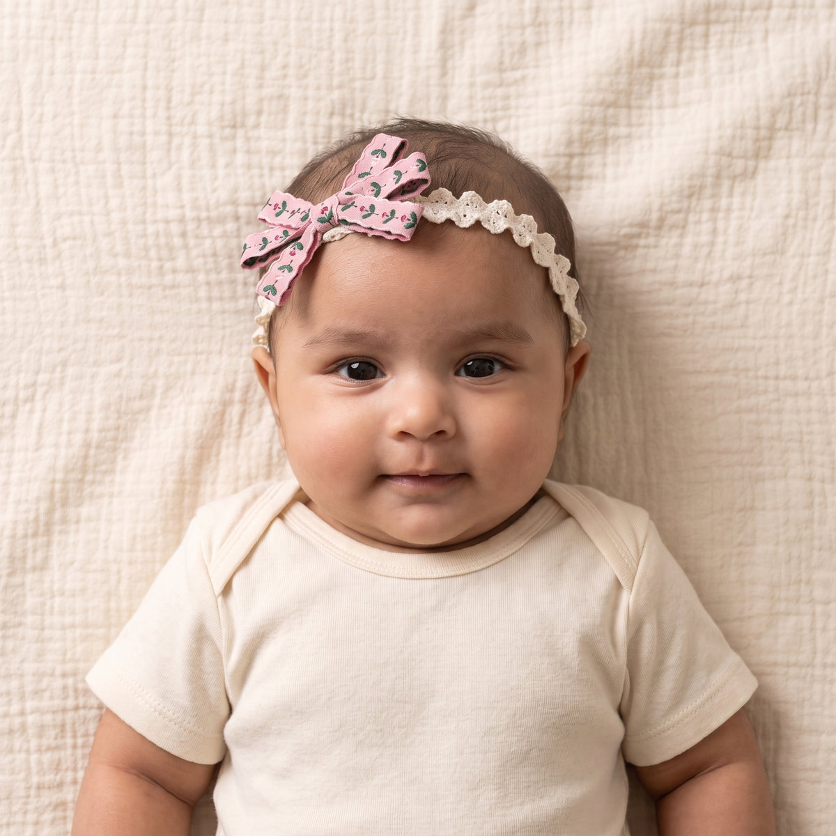 two bobby Embroidered Floral Lace Headband – Pink, worn by a baby