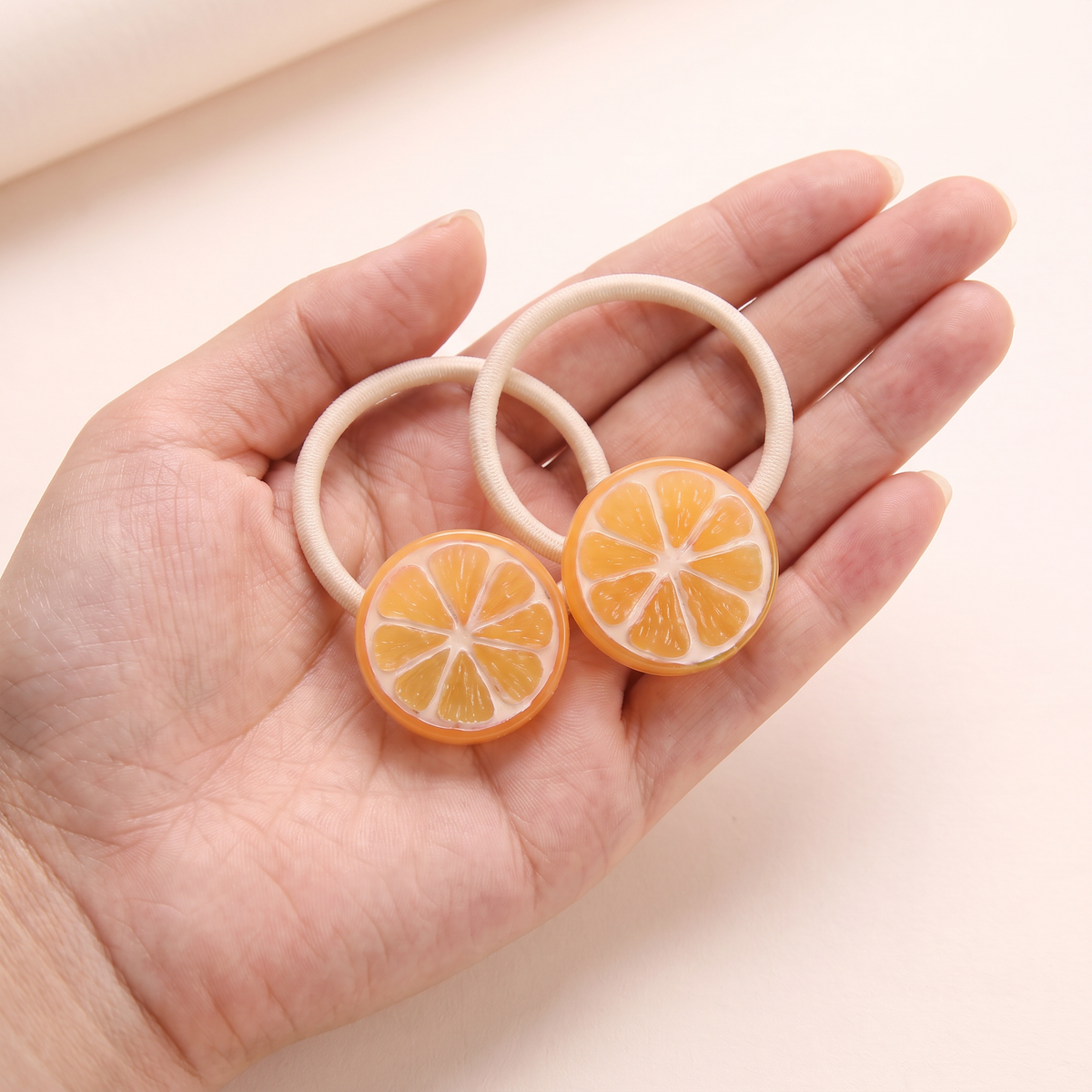 two bobby Fruit Slice Hair Ties – One pair in hand, for size