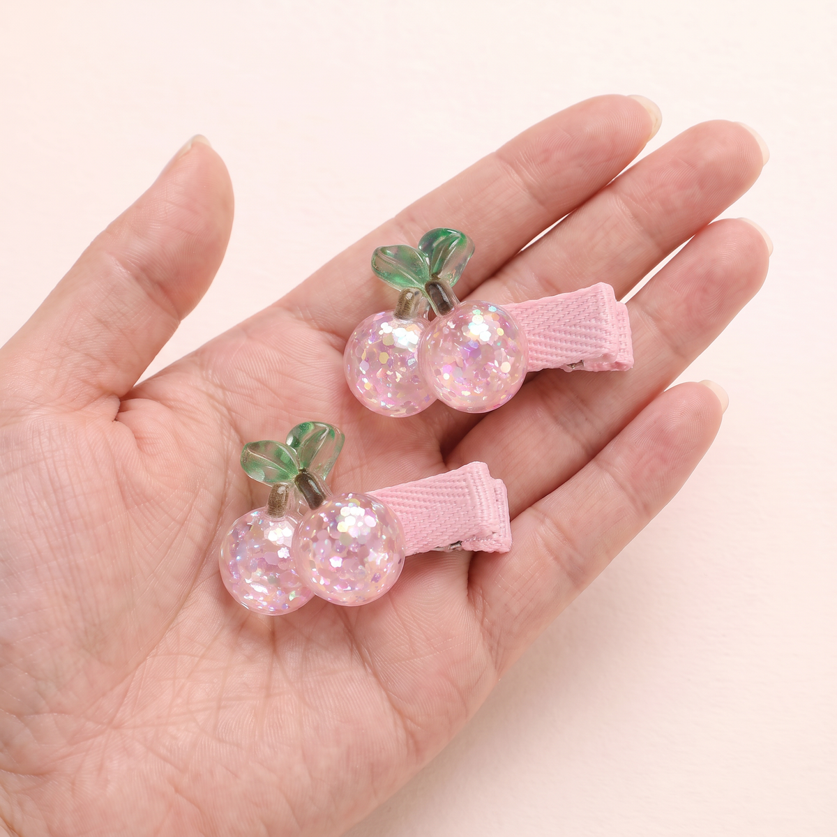 two bobby Glitter Cherry Clips – One pair in hand, for size