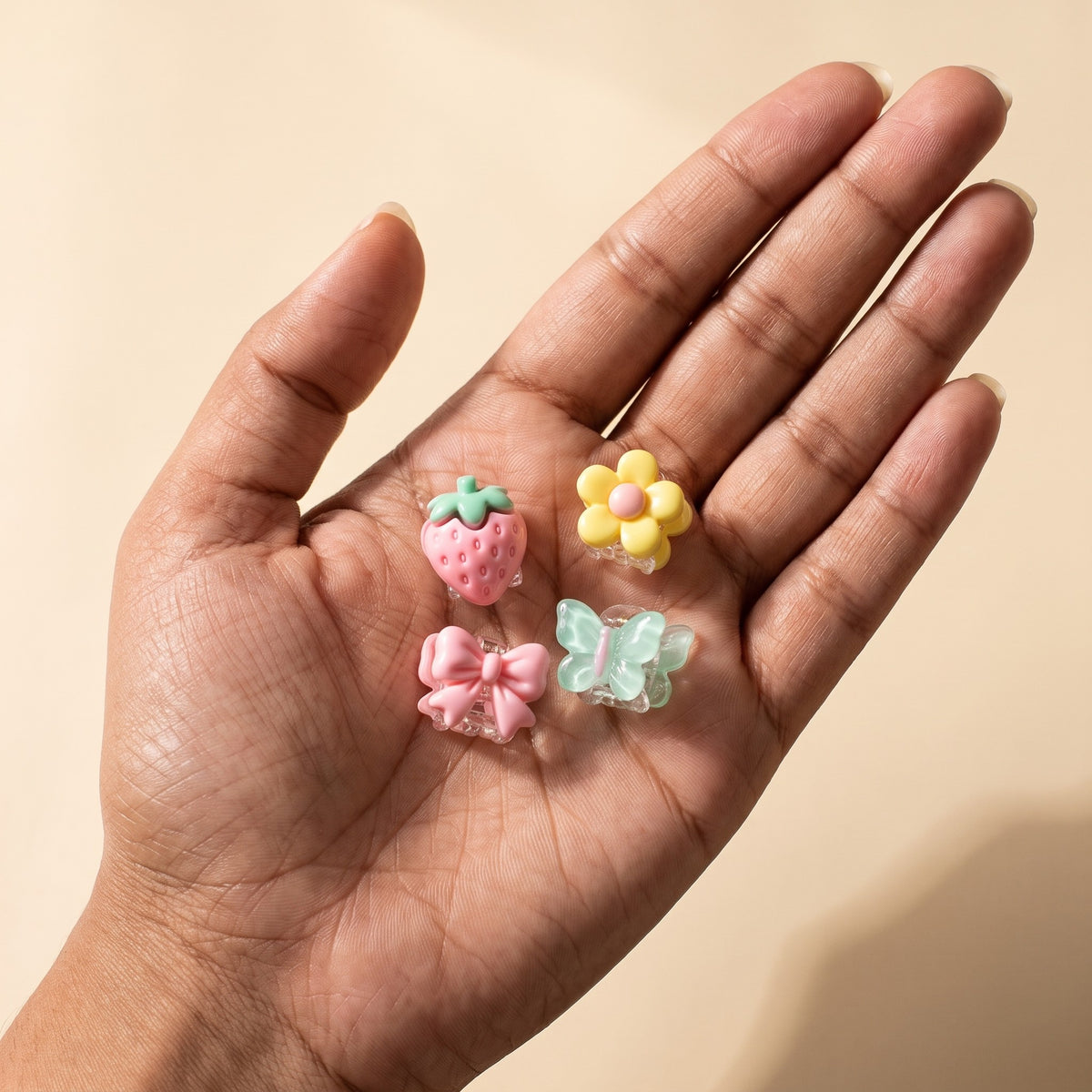 Four charm mini claw clips in a hand, each about 2.5 cm