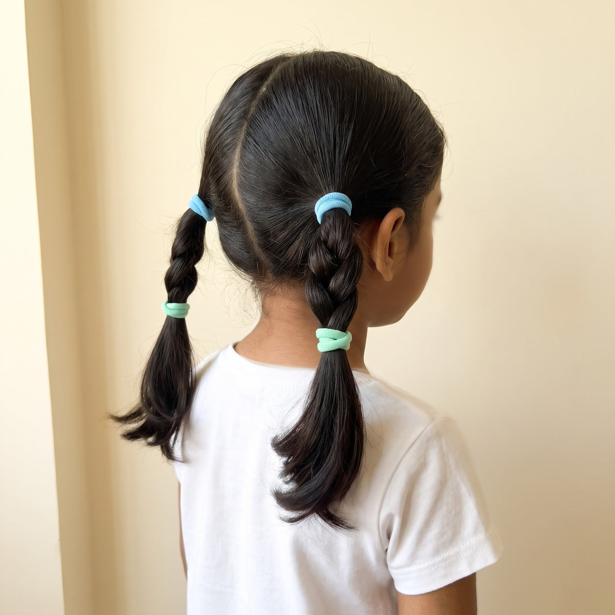 Girl wearing two of the hair ties in plaits, back view