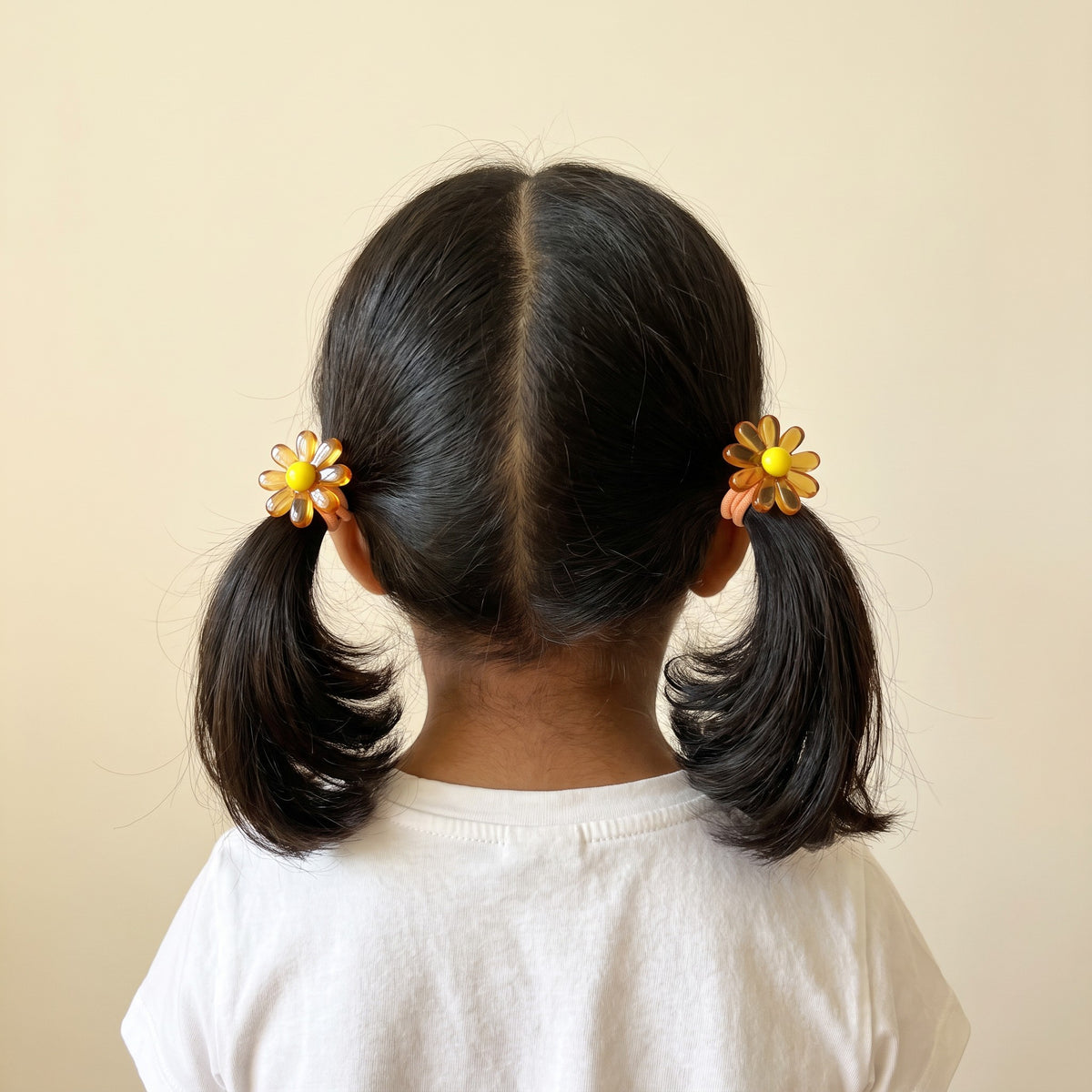 Girl wearing honey jelly daisy hair ties in two pigtails, back view