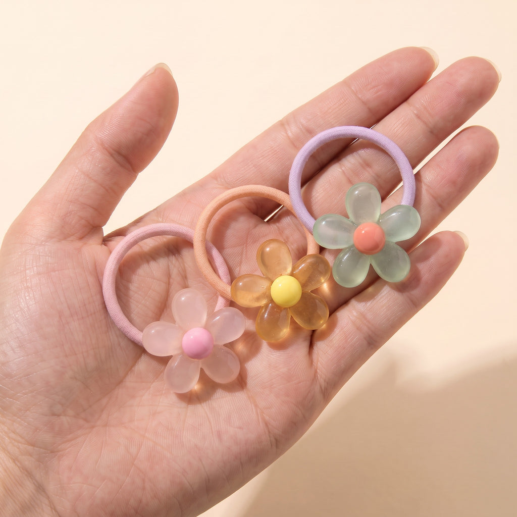 Jelly daisy hair ties in blush, honey and mint held on an open hand to show their size