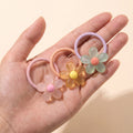 Jelly daisy hair ties in blush, honey and mint held on an open hand to show their size